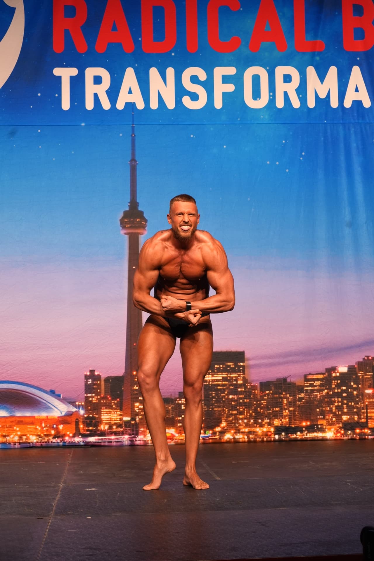 Mikey Bars posing on stage at his first bodybuilding show